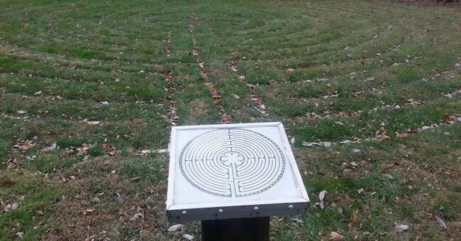 Photograph of a labyrinth marked in brick in the ground, with a labyrinth map.