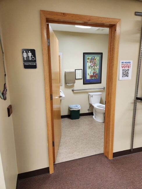 Single-toilet restroom with space and hand bars, meeting the requirements of the Americans with Disabilities Act