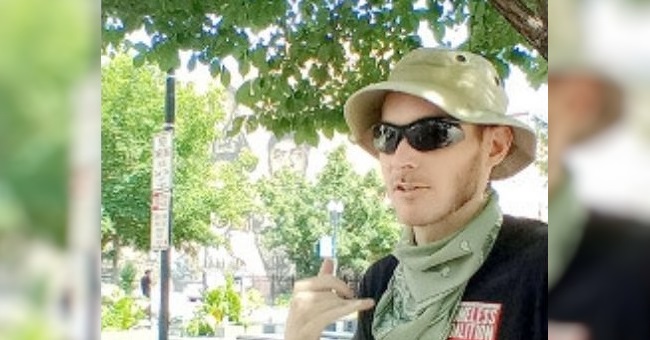 A man in sunglasses shaded by trees on a city street.