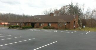 An empty parking lot, with the brick building of Heritage UU Church on the other side.