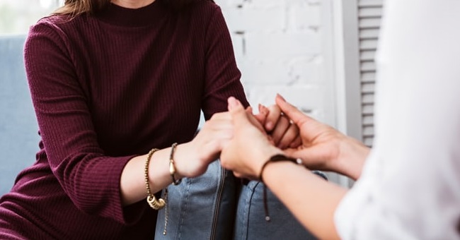 The hands of two women, clasped in care and concern.