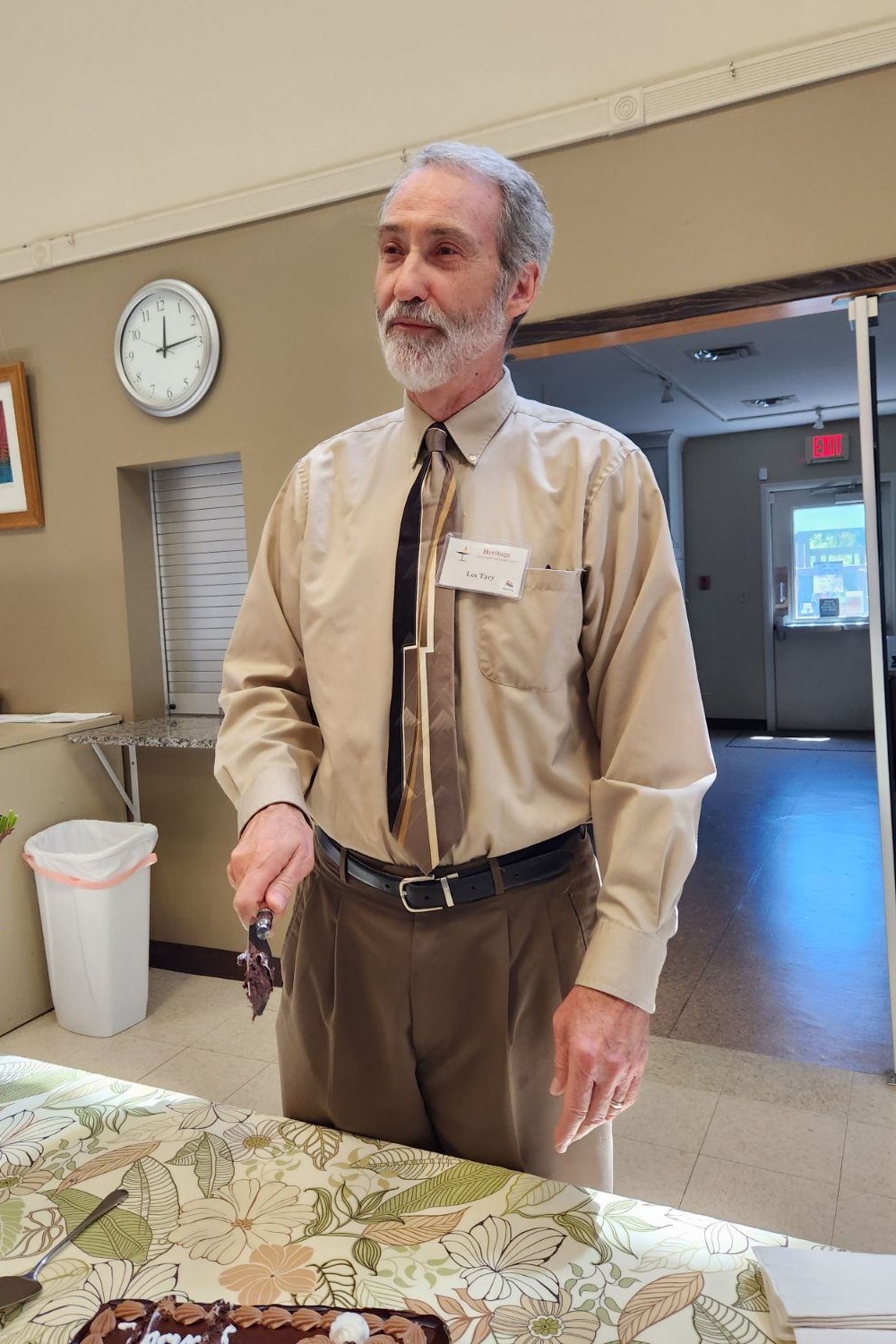 A man stands with a cake knife in his hand, looking out.