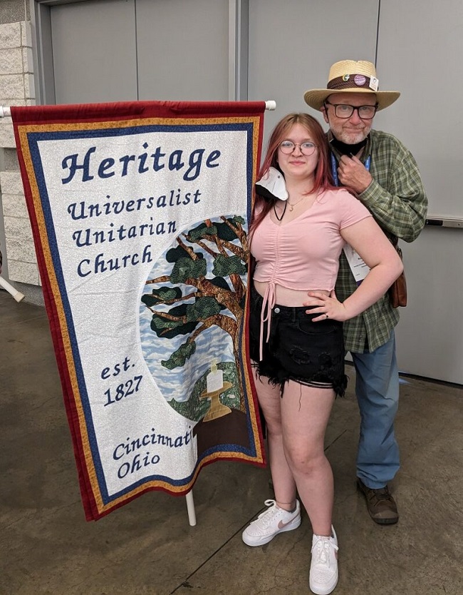 A teen girl and her grandfather holding the Heritage Church banner.