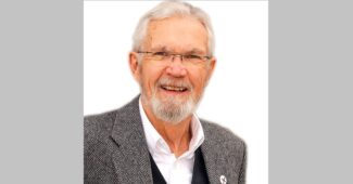 Older man with white hair and beard, smiling at the camera