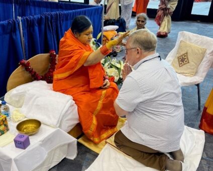 Aa man in western clothing kneels in front of a woman in Indian garb.